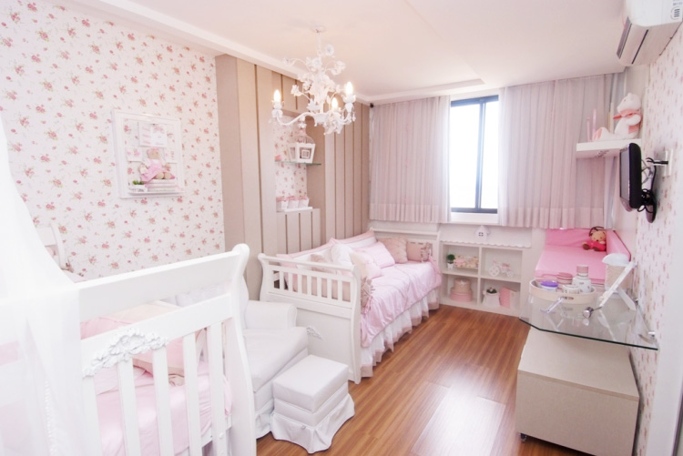 Projetado pelo escritório Melo & Brito, este quarto tem estilo provençal. O piso é laminado durafloor com textura natural de madeira. Todos os móveis têm tons claros e suaves. Para disfarçar uma coluna saliente, foram criados painéis verticais junto com um nicho para decoração -- o que proporciona a leveza ao ambiente. O lustre tem ramos de rosas com pingentes de cristal e as paredes são revestidas com tecido floral.