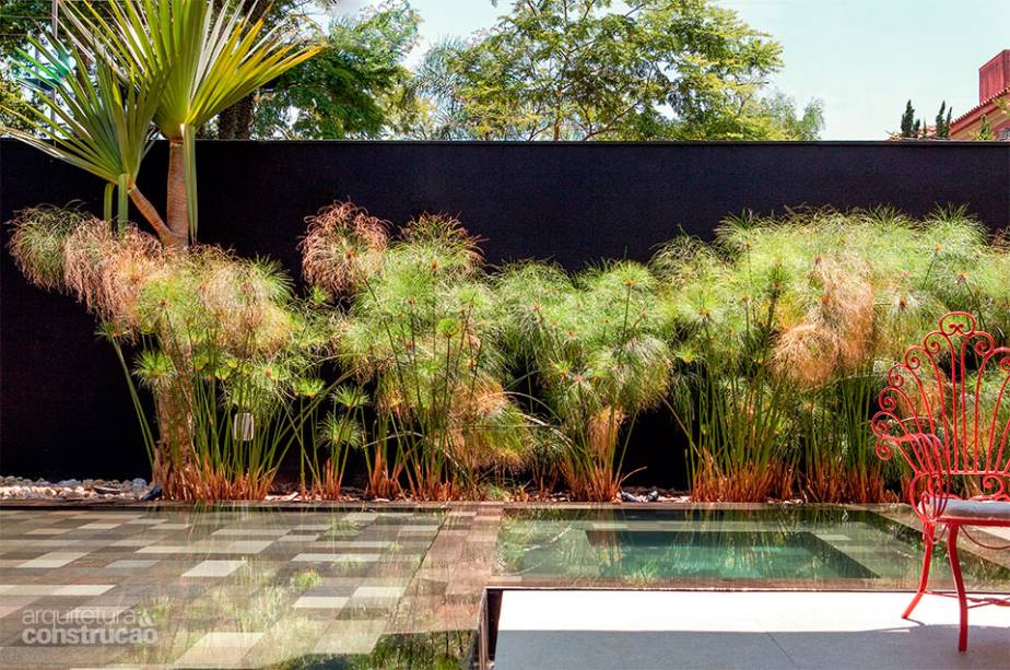 Com área rasa para uma prainha e outra para um spa, a piscina, revestida de pedras vulcânicas, ganhou ares de lago ao refletir a vegetação do entorno e muda de matiz conforme a variação de luz. O verde dos papiros é realçado pela textura preta do muro. Paisagismo de Alex Hanazaki.