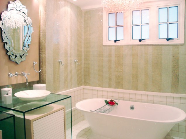Para a suíte do casal entre 40 e 50 anos, a designer de interiores Ana Lucia Martins criou um banheiro clássico com um toque mais atual. A profissional colocou embaixo da cuba, separado por uma caixa de vidro, um armário em laca.