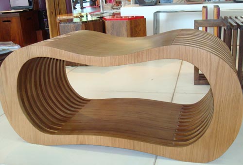 A designer Denise Bahia usou compensado de madeira para dar forma ao banco/revisteiro Feijão. As curvas da peça imitam a semente que é uma das bases da alimentação do brasileiro.