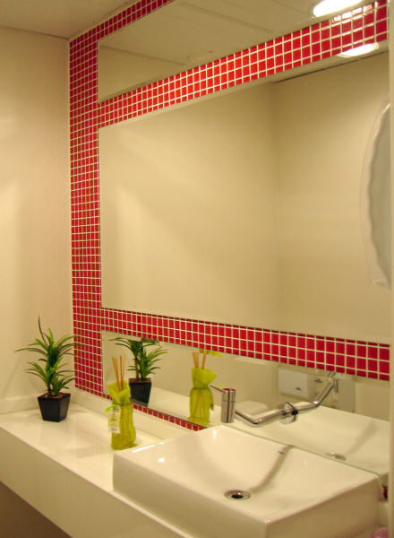 As pastilhas vermelhas não pesam no ambiente pois a arquiteta Paula Nicolini as utilizou somente entre os três grandes espelhos - e deixou todo o resto do lavabo com cores neutras.