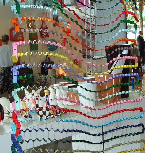Fixadores de etiqueta e fitas coloridas de tecido formam o painel montado pela carioca Karol Picher. A obra faz parte do projeto Novo Desenho , que reúne peças de grandes designers brasileiros.
