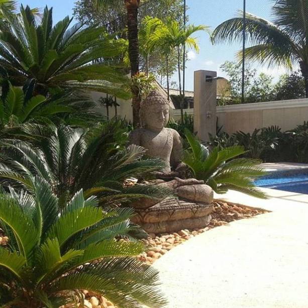 Jardim com espécies resistentes ao clima tropical, como sagus, filodendros, strelitzias e coqueiros, chamam a atenção para a área externa desta casa na Barra da Tijuca, no Rio de Janeiro (RJ). Tons neutros e piso em travertino bruto completam a decoração externa. O projeto é assinado pelo escritório Carmen Moura Paisagismo.