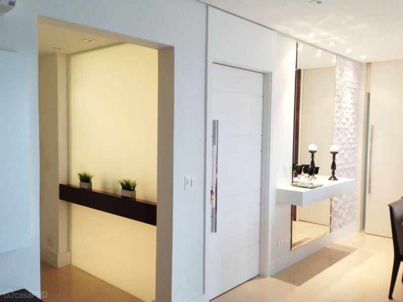 Hall de entrada de apartamento residencial. Separado por parede de vidro serigrafado fixo, com aparador de madeira que serve a ambos os lados. Piso de limestone Mont Dore. Projeto de AT arquitetura.
