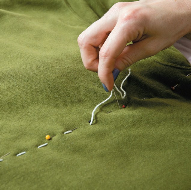 Estique o blusão e marque com alfinetes uma linha reta de uma axila a outra. Se preferir, use régua e giz para riscar o tecido. Costure unindo frente e costas da malha, acompanhando o traçado. Retire os alfinetes.