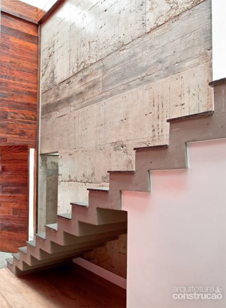 CONCRETO À VISTA. A parede na lateral da escada é uma das faces do volume de concreto armado que integra o desenho desta casa, assinada pelo arquiteto Frederico Zanelato. Embaixo, ele encerra o lavabo. Em cima, outro banheiro e a caixa-d’água. “O concreto resolveu tanto a questão estrutural como a de acabamento: outro material não me daria a mesma possibilidade”, justifica Frederico, que se inspirou no brutalismo, vertente do modernismo de meados do século 20 representada por nomes como Paulo Mendes da Rocha. “A ideia de assumir a construção sem subterfúgios me encanta.” Até os buracos resultantes dos vazios na forma de madeira permaneceram. “É como na vida, um exercício de aceitar as imperfeições.” CONCRETO À VISTA. A parede na lateral da escada é uma das faces do volume de concreto armado que integra o desenho desta casa, assinada pelo arquiteto Frederico Zanelato. Embaixo, ele encerra o lavabo. Em cima, outro banheiro e a caixa-d’água. “O concreto resolveu tanto a questão estrutural como a de acabamento: outro material não me daria a mesma possibilidade”, justifica Frederico, que se inspirou no brutalismo, vertente do modernismo de meados do século 20 representada por nomes como Paulo Mendes da Rocha. “A ideia de assumir a construção sem subterfúgios me encanta.” Até os buracos resultantes dos vazios na forma de madeira permaneceram. “É como na vida, um exercício de aceitar as imperfeições.”