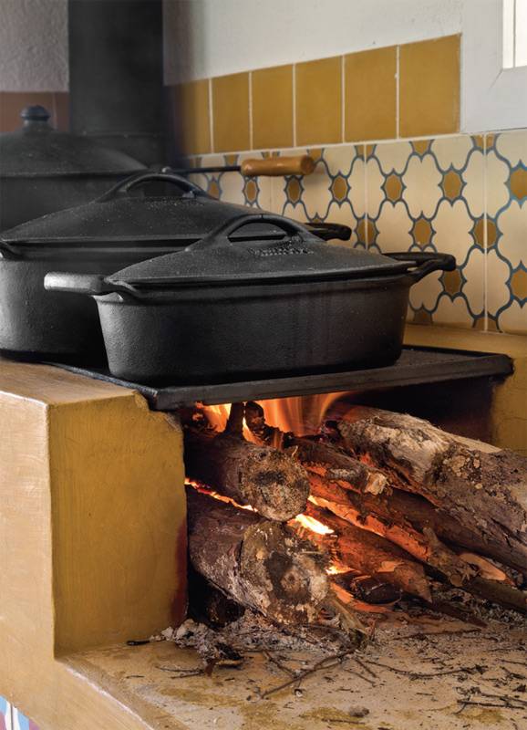 A cozinha completamente integrada ao estar, com direito a um fog&atilde;o a lenha no canto, foi uma exig&ecirc;ncia da moradora que adora subir a serra acompanhada de amigos e muito vinho. A bancada do fog&atilde;o a lenha (Chauffage) foi revestida de cimentado com corante mostarda, executada pelo empreiteiro. Projeto de Renata Bartolomeu.