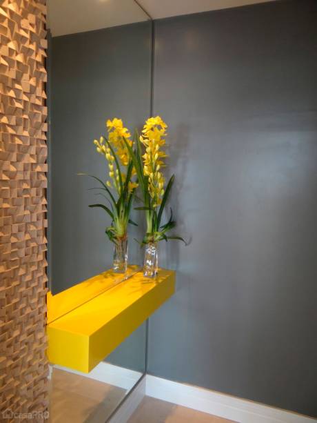 Hall social de apartamento residencial. Piso de limestone Mont Dore com rodapé de MDF branco. Paredes com pintura cor SW 7067 (Sherwin Williams). Aparador com pintura laca amarela, espelho na largura do aparador e na lateral esquerda, revestimento mosaico travertino em cunhas. Projeto de AT arquitetura.