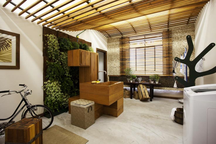 Ambiente projetado pela arquiteta Leticia Wassali para a mostra Campinas Decor, esta lavanderia tem com primeira preocupação a sustentabilidade: por meio de um sistema de tratamento de águas cinzas, a água da máquina de lavar é tratada e utilizada para regar o jardim vertical que ocupa uma das paredes do espaço. Peperômias, colunéias e ripsális ocupam os vasos pendurados no painel composto de placas de vidro.