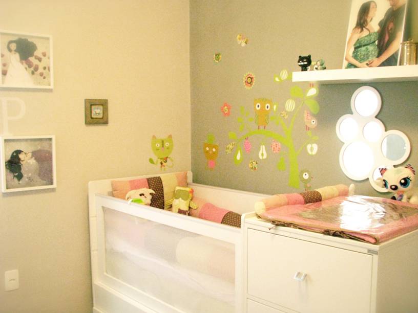A ideia da designer de interiores Samara Junqueira para este ambiente era criar um quarto de menina sem o convencional cor de rosa. As paredes foram pintadas em dois tons de cinza e o mobiliário branco faz o contraste. Ao lado do trocador, espelhos chamam a atenção do bebê e facilitam as trocas de fraldas. Adesivos de parede, alguns desenhados pela própria designer, quadros trazidos de viagens e toyarts compõem o ambiente descontraído.