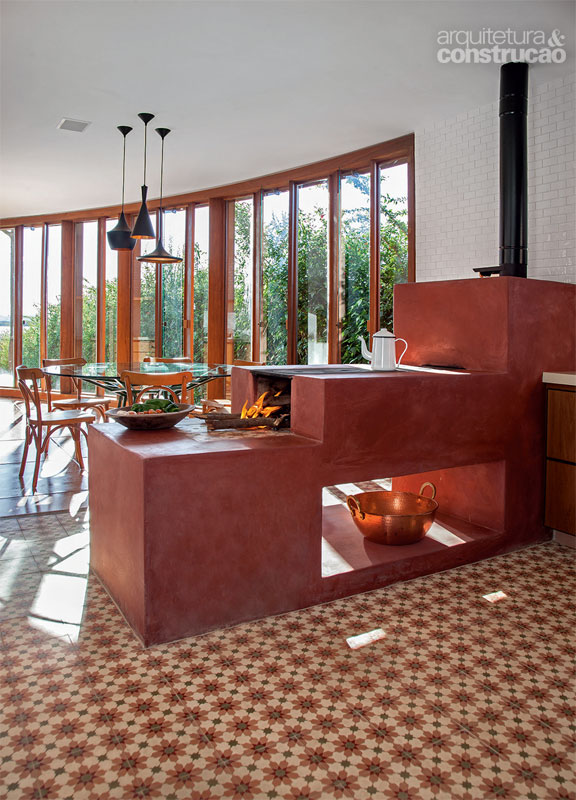 Revestido de vermelhão, o fogão a lenha lembra que a casa está no interior de Minas Gerais. Ele separa a cozinha da área de apoio. Projeto dos arquitetos Marcelo Alvarenga e José Ricardo Fois.