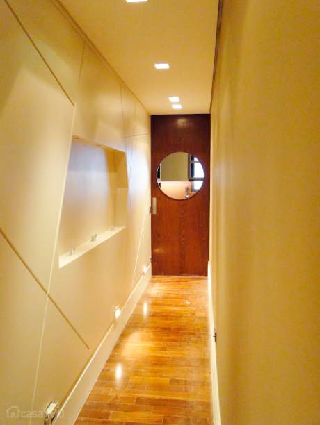 O corredor virou galeria e recebeu um painel de mdf laqueado com desenhos e sulcos de 1 x 1cm traçados a mão pela arquiteta no local. O nicho central serve de apoio para quadros e ganhou iluminação embutida. Projeto de Débora Nanni.
