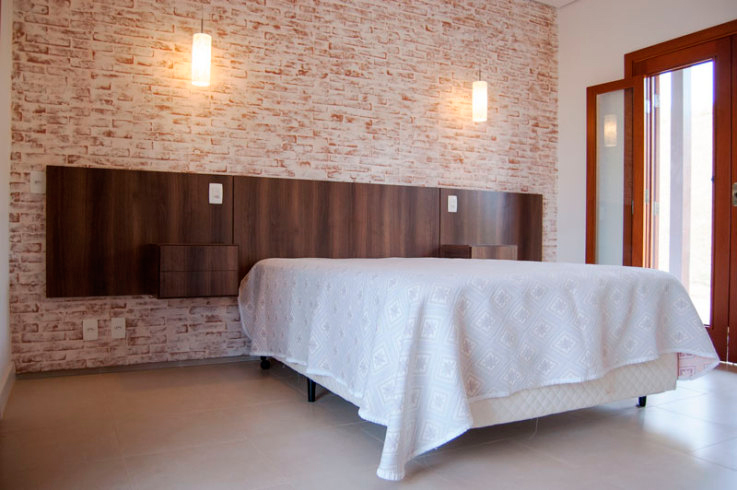 CASA EM JUNDIAÍ. A suíte de hóspedes da casa projetada por Juliana Sorolla Mancini repete o revestimento da parede da área externa: tijolo caiado. Caixilhos de madeira maciça (Ulimax) e piso em porcelanato (Eliane 45x45) completam o ambiente de 15 m².