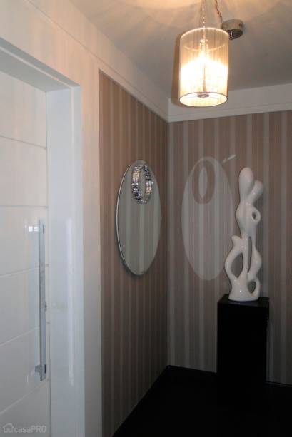 Hall de apartamento com piso laminado Durafloor ébano, papel de parede listrado, escultura em mdf Jadir Battaglia, espelho Metáfora Design. Projeto de Rosa Pinheiro.