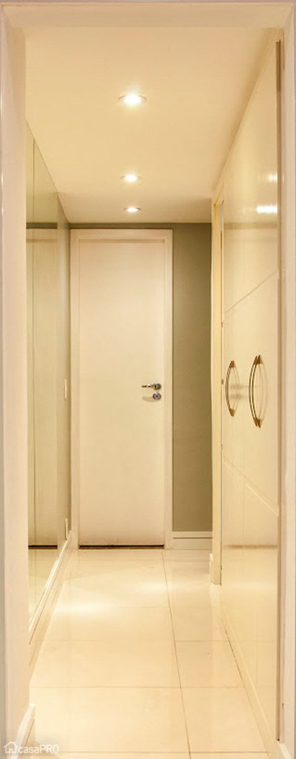 Neste corredor que dá acesso aos quartos e banheiro, foi utilizada tinta camurça da Coral nas paredes, espelhos para ampliação do espaço, rodapés de laca branca e iluminação pontual com dicróicas. Projeto de Millena Miranda.