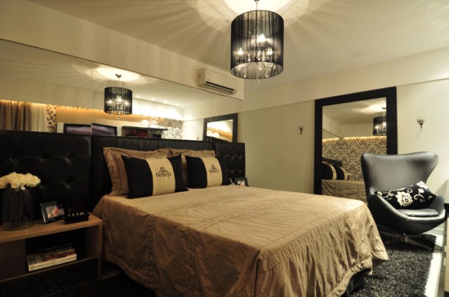 Camila Moraes. Este quarto, de 14,4 m², foi projetado pela arquiteta Camila Moraes. O destaque do ambiente fica por conta da cabeceira da cama, que é estofada e revestida com um tecido sintético semelhante ao couro natural e preto.