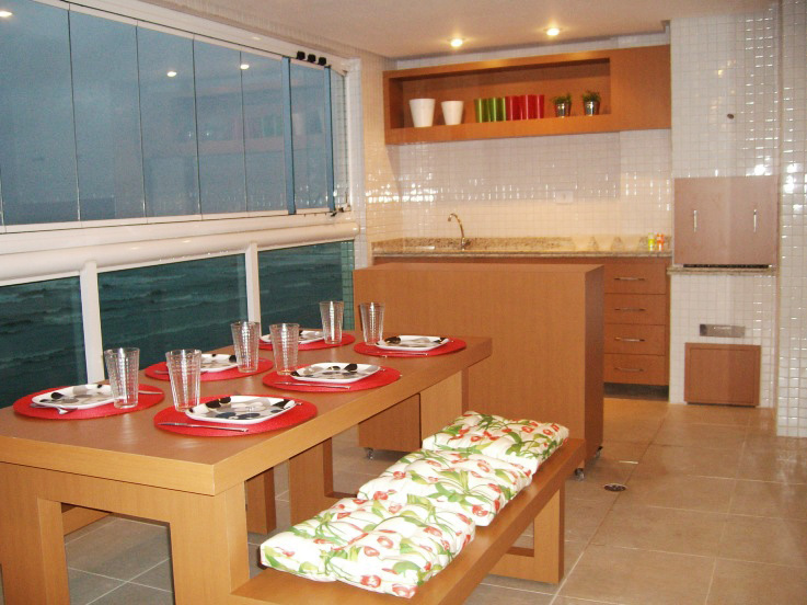As designers Cristina Mussi e Ivone Dias aceitaram o desafio de projetar uma varanda gourmet para um casal que vai morar neste apartamento na praia: apesar da área ser larga e comprida, elas fizeram de tudo para economizar espaço e optaram por um balcão com rodízios e mesa com bancos, para não atrapalhar a passagem. A churrasqueira foi coberta com azulejos brancos.