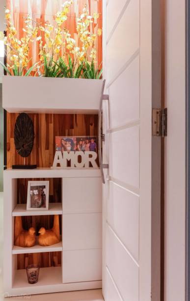 Hall de entrada de um flat. Um pequeno armário de laca branca e fundo em teca foi criado para dividir o ambiente de entrada, sala e cozinha. Marcenaria Maia. Projeto de Gisele Ribeiro Arquitetura.
