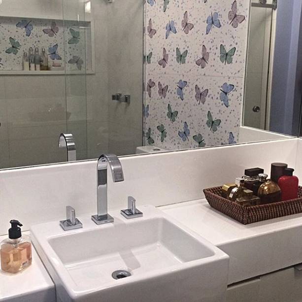 Neste apartamento no Rio de Janeiro (RJ), o banheiro tem revestimento em cores neutras. O colorido ficou por conta do papel de parede com desenhos de borboletas. O projeto é assinado por Luciana Nascimento e Valeska Marques.