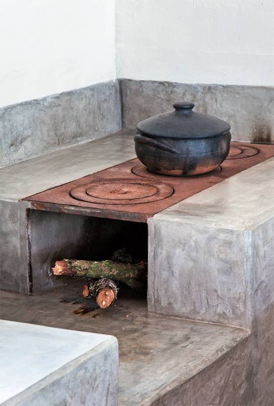 A bancada da pia e o revestimento do fog&atilde;o a lenha foram moldados na obra com cimento estrutural e impermeabilizados depois de prontos com tr&ecirc;s dem&atilde;os de resina &agrave; base de &aacute;gua. Nas paredes, o embo&ccedil;o r&uacute;stico recebeu acabamento de tinta acr&iacute;lica. Projeto Ricardo Hachiya e Luiza Fernandes.