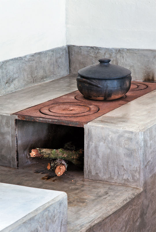 A bancada da pia e o revestimento do fogão a lenha foram moldados na obra com cimento estrutural e impermeabilizados depois de prontos com três demãos de resina à base de água. Nas paredes, o emboço rústico recebeu acabamento de tinta acrílica. Projeto Ricardo Hachiya e Luiza Fernandes.