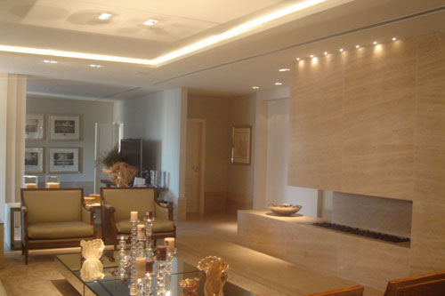 Nesta residência, em São Paulo, o painel de mármore travertino romano que abriga a lareira a gás faz a divisão entre a sala de estar e o bar/adega. A iluminação com leds destaca a peça e compõe a ambientação. Projeto assinado pela arquiteta Cristiana Costa.