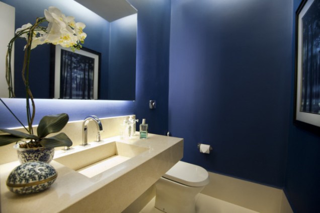 A parede azul ganha um efeito degradê por conta da iluminação indireta do teto e do espelho. Projeto de Berenice L Palhares.