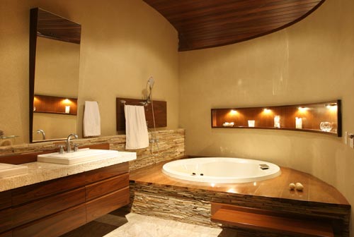 Com 26m², este banheiro foi projetado para o casal relaxar a sós. O piso e bancada foram feitos em mármore bege Bahia. Os detalhes da parede foram criados com filetes de São Thomé. Para trazer aconchego para o ambiente a arquiteta Ana Meirelles usou madeira ipê no deck da banheira, no pranchão e no nicho para velas e sais de banhos.