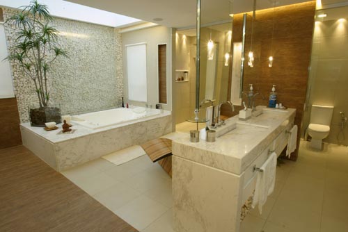 Um ambiente amplo de 34 m2 com uma chaise-longue para a leitura, uma TV de 42’’ e um frigobar. Não parece, mas é um banheiro. O projeto de Ana Meirelles tentou privilegiar a área de convivência do casal, mantendo o espaço para cada um. É por isso que a arquiteta optou por colocar no espaço duas pias – feitas de mármore branco piguês. Além disso, a área da bacia é independente e está isolada por portas de correr em vidro opalinizado. O piso é de porcelanato. As paredes são revestidas de granilita.