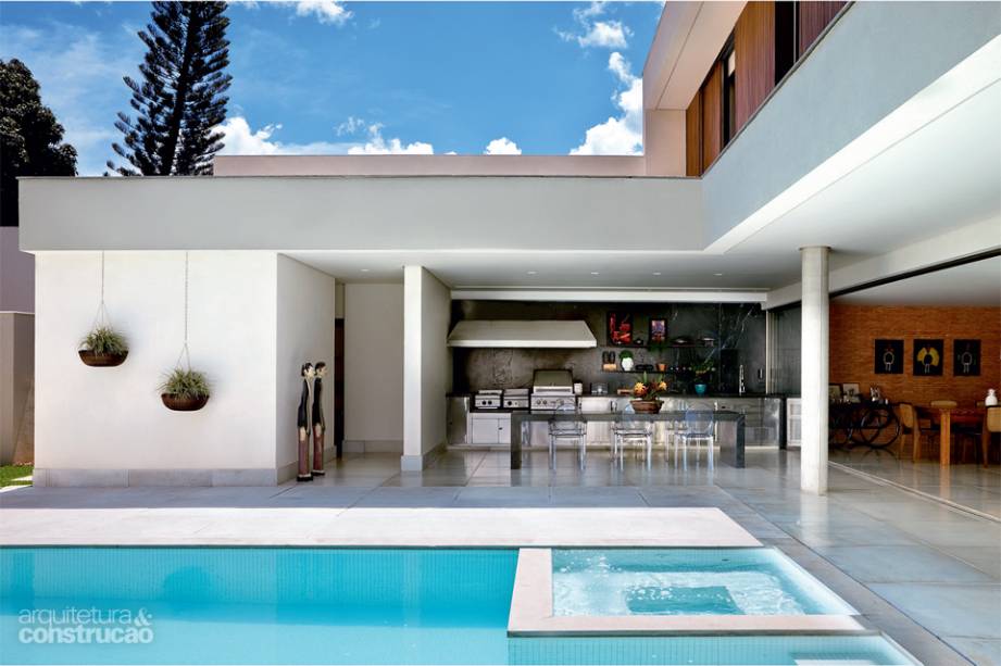 Não há propriamente varandas, apenas uma estreita faixa coberta, que garante a transição entre interior da casa e exterior, onde fica a piscina. As colunas redondas suavizam as linhas retas do projeto. Projeto da casa: Patrícia Almeida.