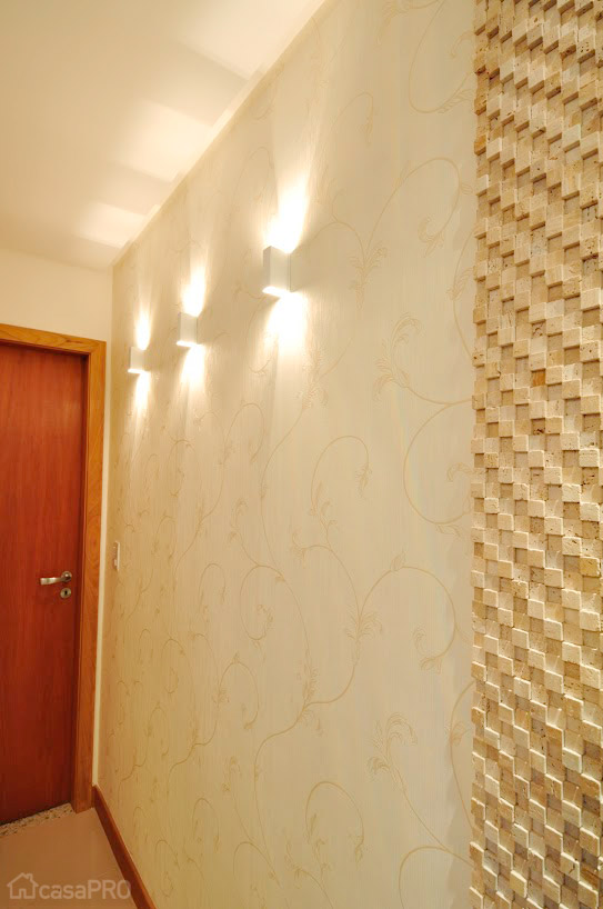 Nesse corredor de 2,90 x 1 m, os destaques são os revestimentos de papel de parede e painel com largura de 90 cm de mosaico cimentício, além da iluminação composta por arandelas de alumínio branco que valoriza todo o conjunto. Projeto de Maristela Lima Bernal.