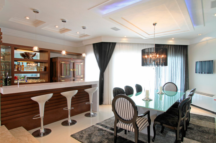Recortes no gesso e pendentes proporcionam uma iluminação difusa e aconchegante ao espaço que une bar e sala de jantar assinado por Michelle Palaver.