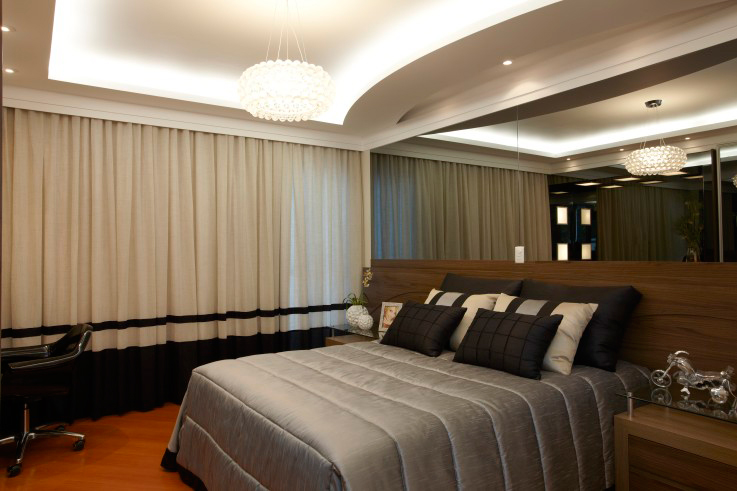 CASA NA SERRA DA CANTAREIRA. Neste quarto, projetado por Aquiles Nicolas Kilaris, um dos destaques é a parede atrás da cama, revestida com espelho fumê. O ambiente, de 21,75 m², ainda traz piso laminado e madeira imbuia na cabeceira.