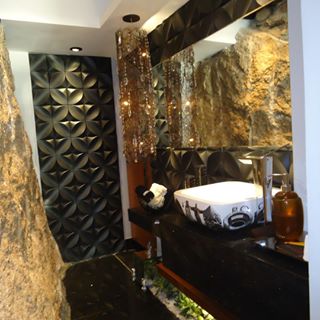 No lavabo da mostra Casa Design 2012, a aruqiteta Priscilla Ramalho optou por destacar a rocha existente no local. Para isso, o preto São Gabriel foi escolhido para piso e bancada. Ao fundo, um painel cimentício.