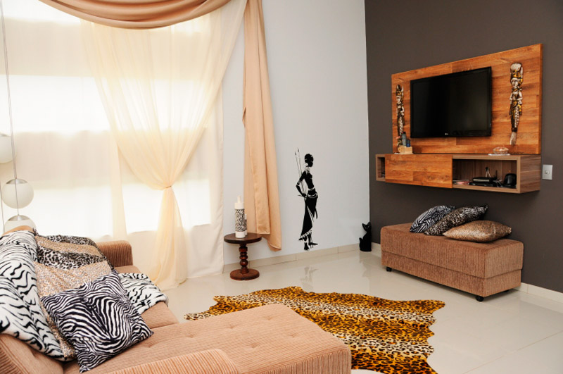 O espaço é uma sala íntima e de TV com aproximadamente 18m². A inspiração do ambiente gira todo em torno das estampas animais e as influências africanas. Na parede, foi adesivada uma mulher tribal. Projeto de Wagner Giongo.