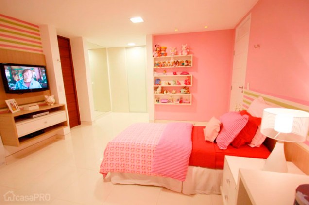 O quarto feito para uma menina de 6 anos é todo em rosa - a moradora ama a cor. As paredes rosa são pintadas e as partes com listras coloridas são feitas de tecido. Projeto das arquitetas Larissa Vinagre Suellen Montenegro.