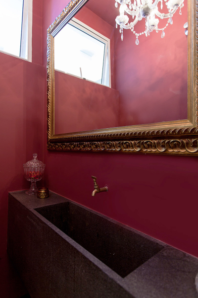 O banheiro de empregada deste apê foi aberto para o hall e virou um lavabo de impacto, com paredes na cor vinho. Projeto de Tria Arquitetura.