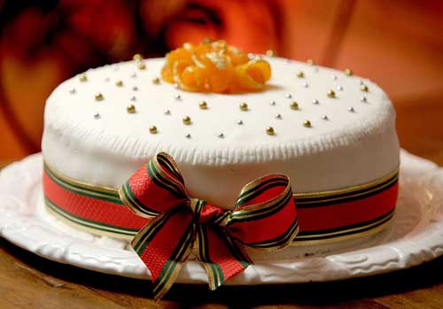 O bolo de chocolate do Carlota vem com cobertura branca e um laço vermelho, ...
