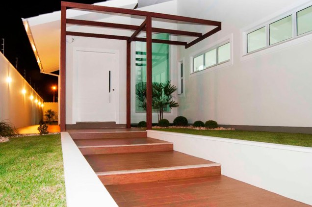 Residência de alvenaria com pergolado de madeira na entrada. Projeto de Paula Corrêa Pereira.