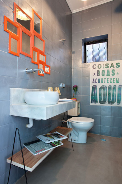 O cinza da parede deste lavabo vem do revestimento escolhido pelo escritório Martinhão Neves Arquitetos. Repare que o espelho é como um mosaico de peças simples e pequenas.