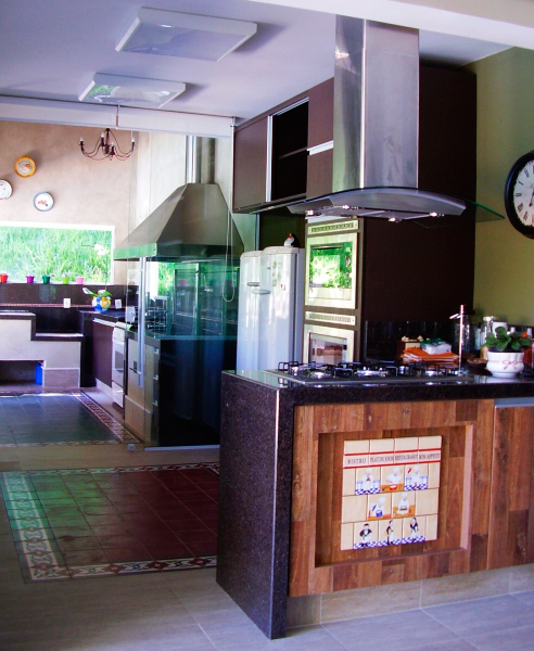 CASA NO INTERIOR DE SP.  A porta de vidro separa a cozinha gourmet e a churrasqueira, nesta casa de campo projetada pela arquiteta Rosane Aguiar. No chão, um tapete de ladrilhos hidráulicos é destaque.