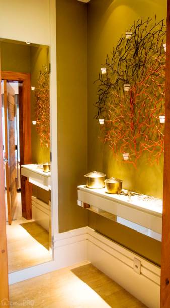 Parede com pintura verde escuro. Neste espaço, existe uma porta da parte elétrica do edifício e nela um espelho com bisotê. Foram usados rodapés de laca branca com 40 cm de altura. Aparador também em laca branca brilhante com detalhe em espelho. Piso de mármore travertino. Porta de entrada em madeira de demolição rústica com acabamento polido no contorno. Projeto de Manoela Lustosa da Silva.