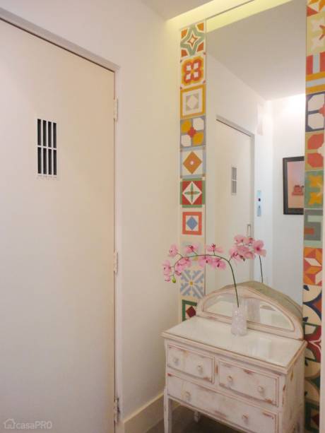Hall de elevador de apartamento. Um móvel antigo do cliente, clareado com pátina,  foi reaproveitado no espaço - assim como a sobra dos ladrilhos hidráulicos usados no banheiro, que viraram moldura para o espelho. O objetivo era que ficasse diferente e econômico. Projeto de Maria Helena Torres.