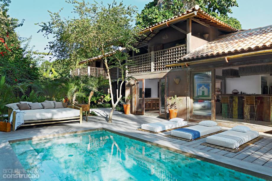 Perto da piscina, a área social inclui sala de TV, cozinha colada à churrasqueira – similar aos exemplares argentinos, que levam chapas de ferro de forno siderúrgico – e sala de jantar. O tanque foi revestido de placas de ônix da palimanan. Projeto de Daniela Oliveira.