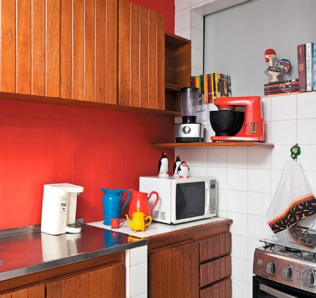 Jarras e açucareiros velhinhos conquistaram visual pop na cozinha após um banho de cor. Os azulejos brancos receberam uma camada de tinta vermelha, que contrastou com os armários de madeira e com a geladeira de inox. Projeto de Valentina Rocha.