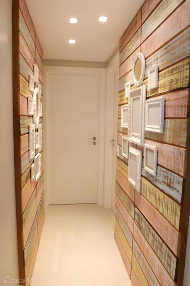 O corredor de 3,30 m² possui painel de madeira de demolição com resto de tinta e quadros laqueados brancos. Projeto de CAS Arquitetos Associados.