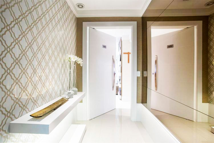 Hall de entrada de apartamento com papel de parede da Bucalo Book Waverly, painel em espelho bronze da Pura Art Vidraçaria e prateleira de marcenaria iluminada da Espaço Interferência. Projeto realizado pela Le Haus Arquitetura em parceria com a Elementhos Projetos.