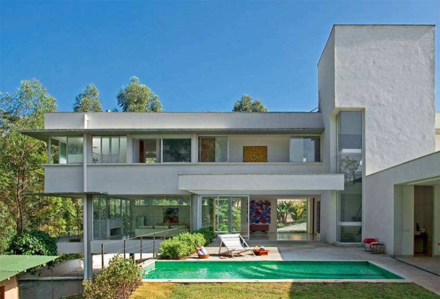 A casa toda oferece transparência. Até a torre da escada (bloco mais alto) tem um rasgo com vidro temperado e caixilho dealumínio sem montantes, o que confere vista privilegiada a essa área de circulação. A piscina de concreto foi revestida com pastilhas de vidro. Projeto de Marcio Porto.