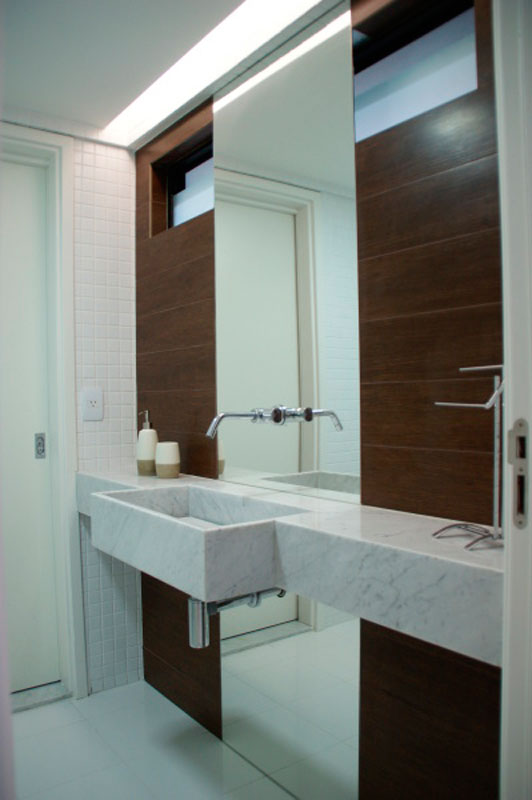 Para o apartamento do casal que pretende usar este banheiro como suíte de um futuro bebê, a arquiteta Carolina Mota revestiu o ambiente com um porcelanato que imita madeira. A inovação deste projeto é a torneira rosqueada no próprio espelho.