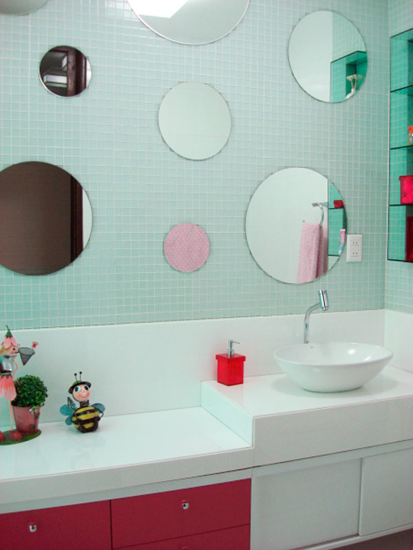 Para o banheiro de um menino de 10 anos, a arquiteta Janete Barros precisava criar uma atmosfera masculino que atendesse as necessidades e gostos de um garoto. Para isso, optou por um revestimento azul na parede, que foi coberto por vários espelhos redondos, deixando o ambiente mais dinâmico e lúdico.